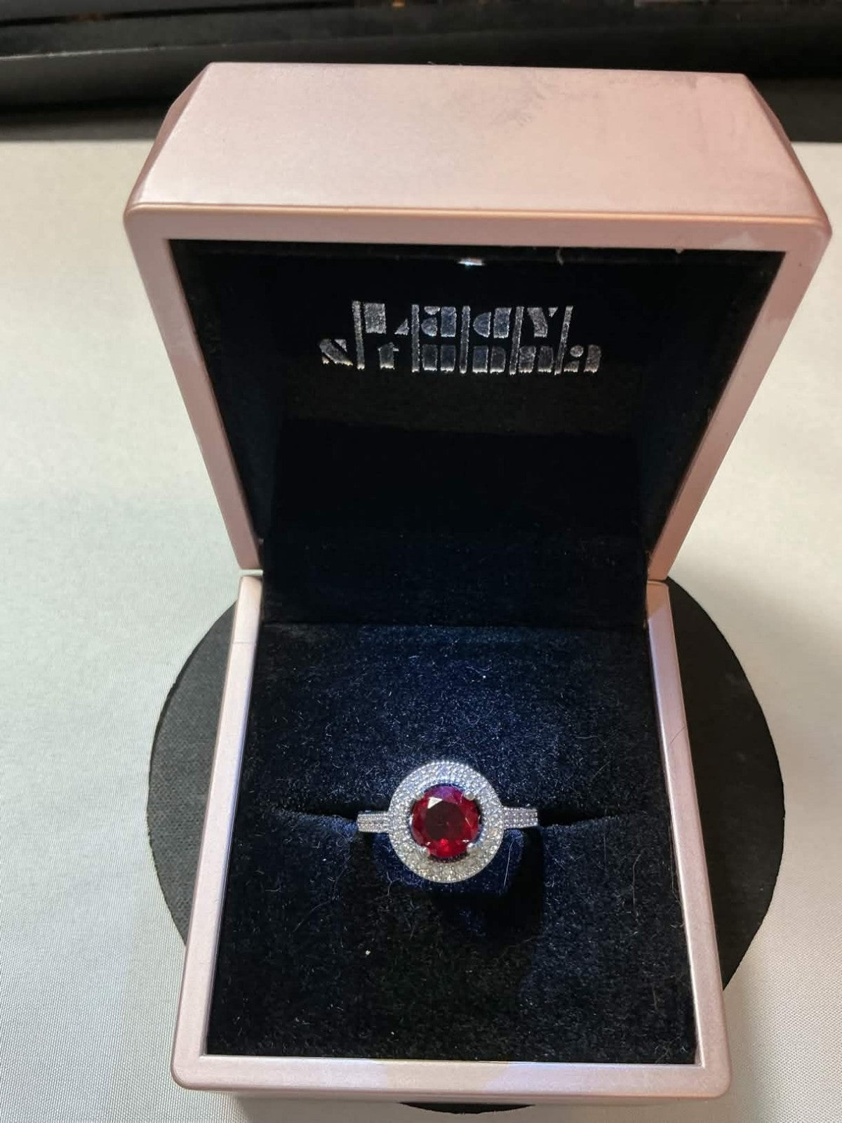 halo-style ring featuring a central red ruby gemstone surrounded by smaller acce