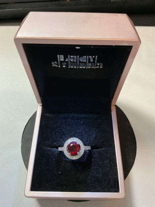 halo-style ring featuring a central red ruby gemstone surrounded by smaller acce